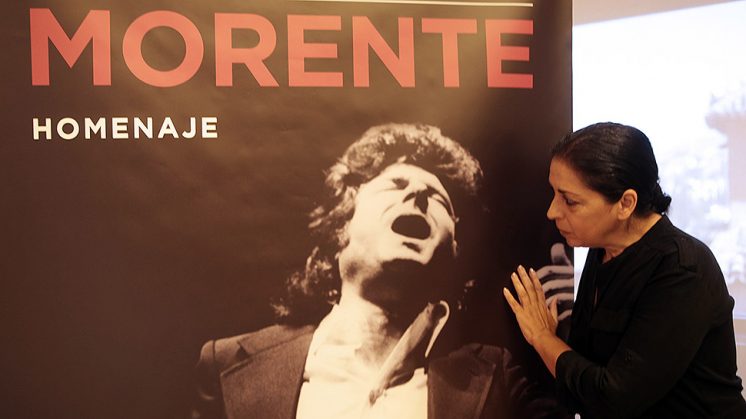 La viuda de Enrique Morente, Aurora Carbonell, junto al cartel que rinde homenaje al artista. Foto: AG.